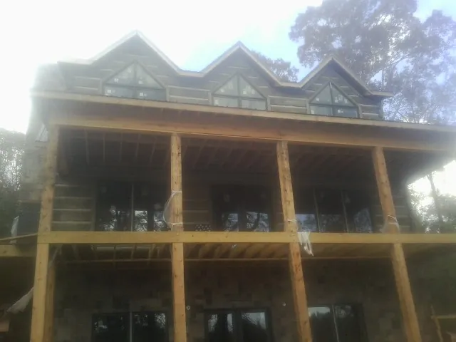 Dormers and porch framing on a large log home under construction — Roof Coating work by our crew in Irving