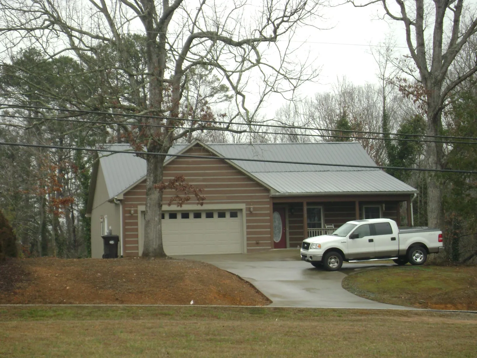 Gray metal roof on a log sided house with an attached two car garage in Irving